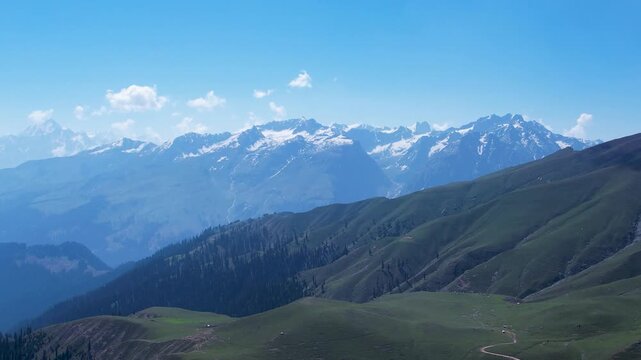 Snow-covered Hindu Kush peaks rise above rolling green hills, Dasht e Laila, Kalam, Khyber Pakhtunkhwa, Pakistan