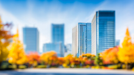 Fototapeta premium ビルと紅葉の木々に囲まれた青空広がる秋のぼかし都市風景