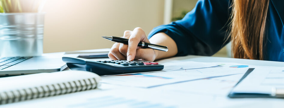 Women business people use calculators to calculate the company budget and income reports on the desk in the office.