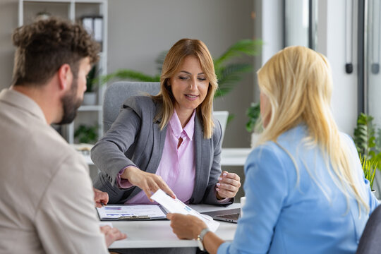 Business consultant meeting with Caucasian American couple in modern office discussing documents and finance