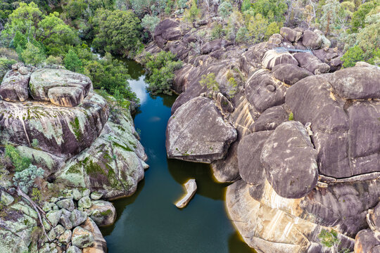 Aerial view of the natural rock pool and striking granite rock formations at Cranky Rock Nature Reserve near Warialda, NSW. Carved by Reedy Creek and surrounded by native bushland