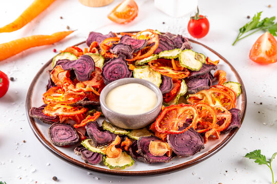 Healthy alternative for traditional potato chips, snack air fried vegetables chips, raw organic dehydrated veggie chips, beets, carrots, zucchini, kale, tomatoes, with white sauce dip