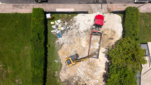 Aerial view of an excavator loading construction debris into a dump truck