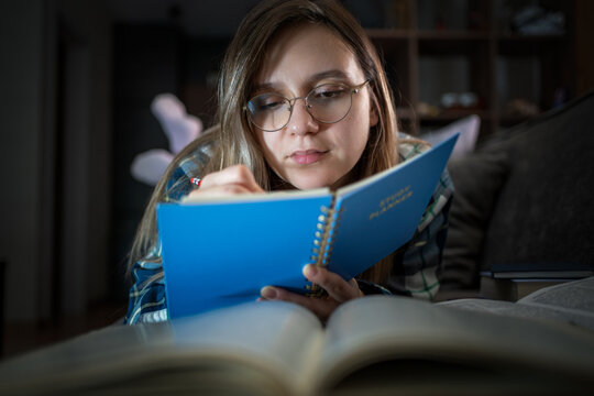 Bored, college student answers of test, paper and person with bulb for dark. night and learning for exam, exhausted of research. young woman is writing an essay in preparation for her studies at night