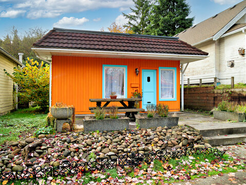 Charming Orange Small House with Teal Door and Picnic Table in front