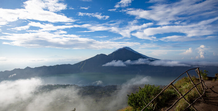 A breathtaking view of the active Mount Gunung Agung volcano emerging from a sea of clouds within  National Park during early morning light.