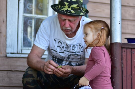 Heartwarming outdoor portrait of a grandfather showing something to his curious granddaughter. Authentic family moment highlighting love, learning, inter generational bonding, care, and togetherness.