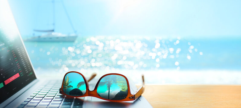 Laptop on the beach with sunglasses reflecting tropical view, freelance remote work concept with ocean bokeh
