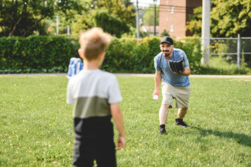 Obraz premium Father and son playing baseball in sunny day at public park