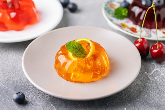 Glossy orange, cherry and blueberry jelly desserts garnished with fresh berries