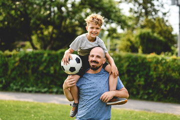 Naklejka premium man with child playing football outside on field