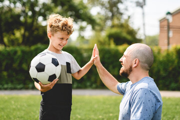 Obraz premium man with child playing football outside on field