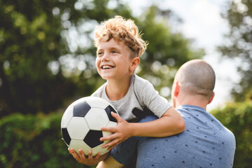Obraz premium man with child playing football outside on field