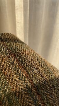 Close-up of olive green textured carpet with subtle red flecks meeting sheer cream curtain, showcasing interior design and home decor elements for residential styling.
