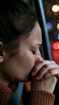 Woman crying in car at night with blurred city lights outside the window