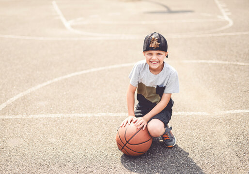 portrait of a boy kid playing with a basketball in park