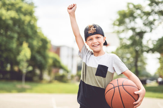 portrait of a boy kid playing with a basketball in park