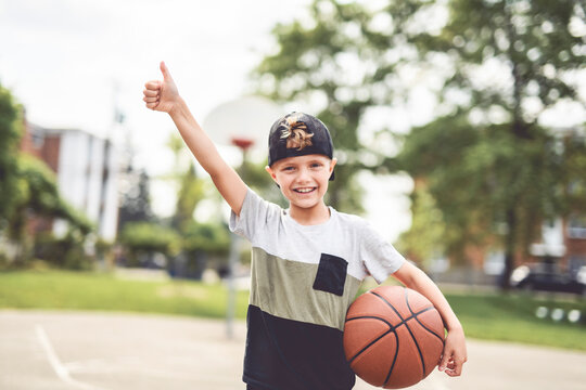 portrait of a boy kid playing with a basketball in park