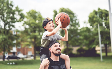 Fototapeta premium man and young boy playing basketball on a court, teaching little player and spending time outdoors