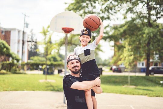 man and young boy playing basketball on a court, teaching little player and spending time outdoors