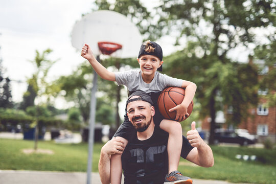 man and young boy playing basketball on a court, teaching little player and spending time outdoors