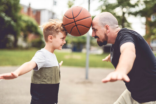 man and young boy playing basketball on a court, teaching little player and spending time outdoors