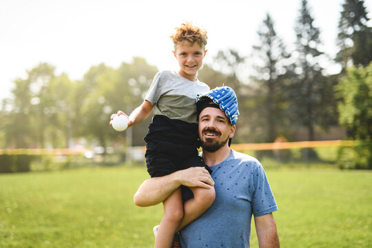 Father and son playing baseball in sunny day at public park