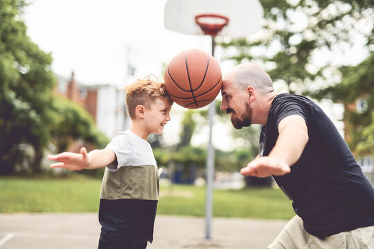 man and young boy playing basketball on a court, teaching little player and spending time outdoors