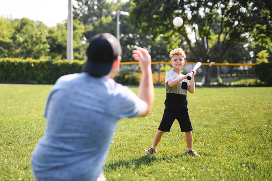 Father and son playing baseball in sunny day at public park