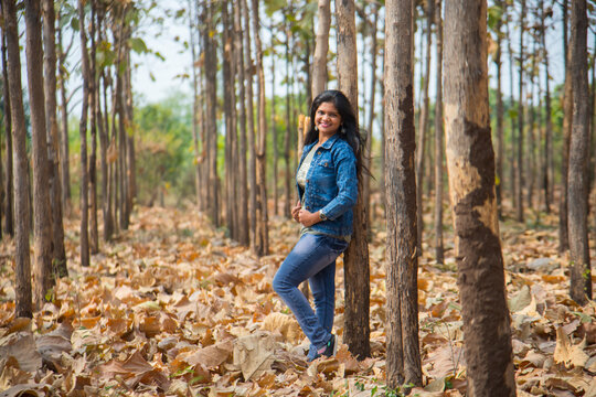 Happy Indian young woman in autumn forest
