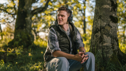 Obraz premium Young man enjoying music in peaceful forest environment