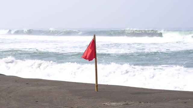 A red flag on the beach indicates a dangerous area.