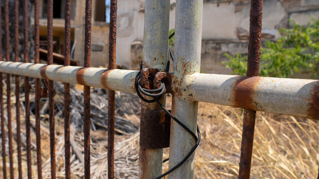 Rusty gate stands broken and abandoned
