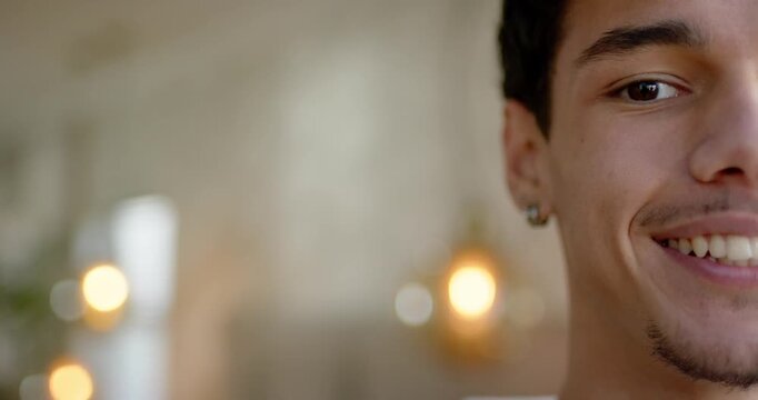 African American man leaning, smiling laughing at home with ear stud, bokeh lights, copy space