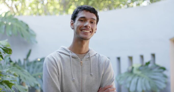 African American man by pale wall with plants as camera reframing, smiling for portrait in hoodie