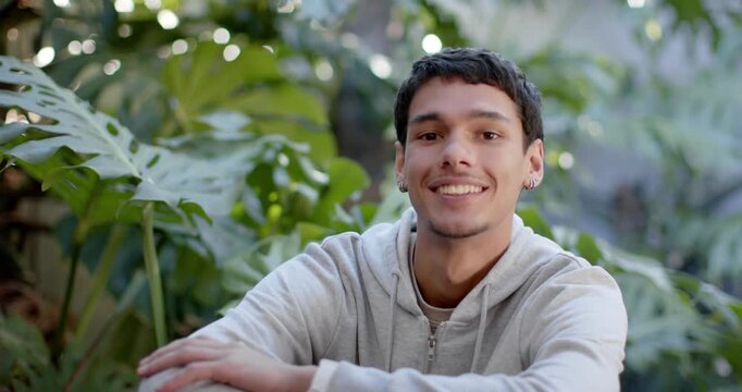 African American male reacting to camera cue, shifting gaze, smiling in garden with tropical leaves