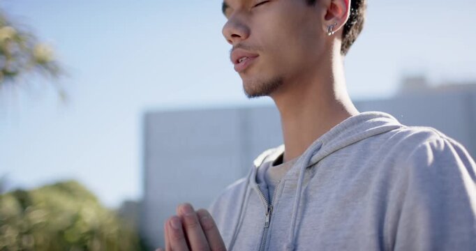 African American man praying for calm on roof in gray hoodie while camera pulling back
