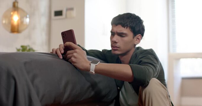 Adult male checking smartphone and leaning along bed edge, feeling for missing item