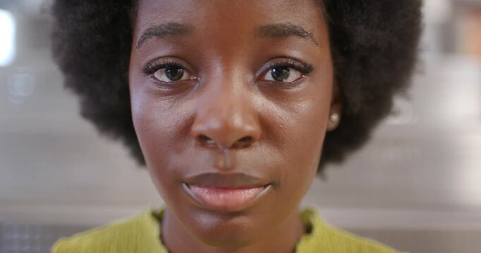 African woman reacting to camera moving closer, smiling into laughing in close-up in green sweater