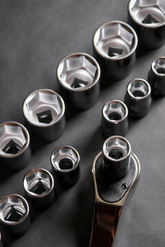 Metal ratchet tool with assorted socket head arranged on a reflective surface in a clean mechanical setup.