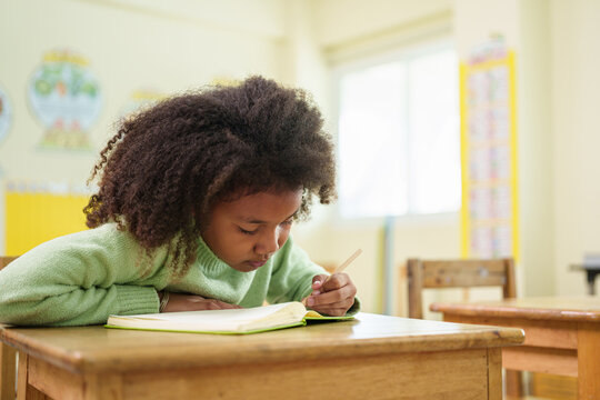 Focused African American student writes during a classroom exam, demonstrating concentration, independent learning, and academic achievement in an elementary school setting.