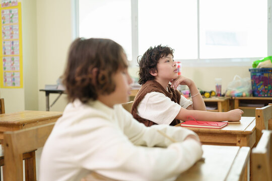 Elementary school students listen attentively during a classroom lesson, showing concentration, active participation, and a positive learning environment.