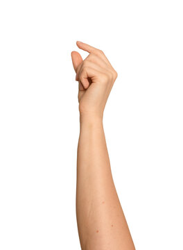 Female hand holds something tiny between thumb and finger. Delicate pinch gesture suggests a very