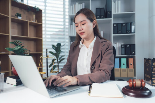 Legal Consultation: Two professionals sit at a desk, carefully reviewing and signing legal documents. In the background a scale of justice rests, and a gavel sits nearby.	