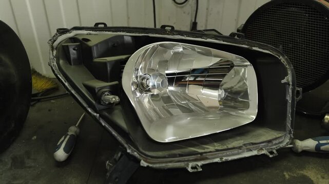 A disassembled car headlight showing the inner chrome reflector housing.