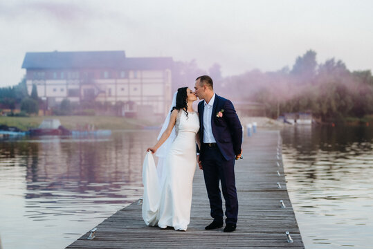 young couple, the bride and groom, walking along a pier
