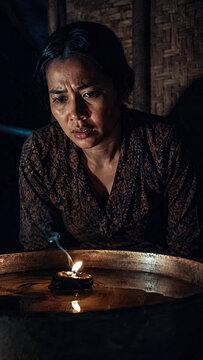 Candlelit portrait of a worried woman holding an empty bowl in darkness.generative AI
