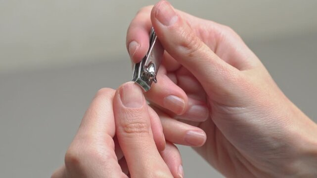 A woman trims her nails with professional metal clippers during a home manicure, paying special attention to hygiene and nail care.