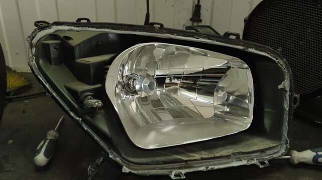 A disassembled car headlight showing the inner chrome reflector housing.