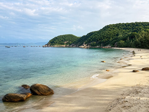 Quiet Hainan cove with clear turquoise water and rounded shoreline rocks.generative AI
